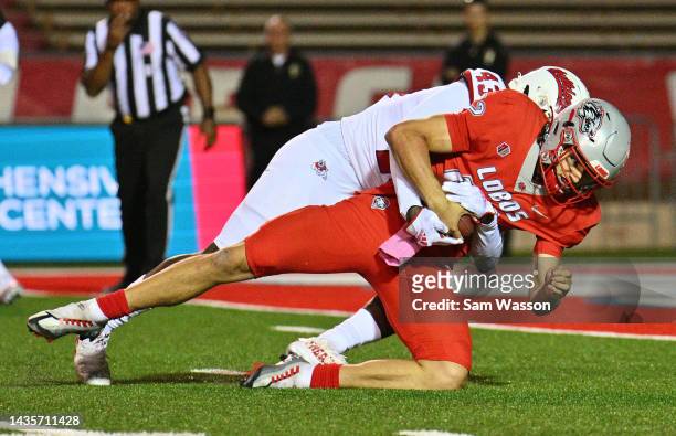 Quarterback Justin Holaday of the New Mexico Lobos is tackled after catching his pass that was batted in the air by defensive back Morice Norris of...