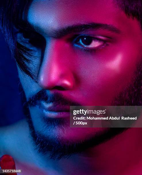 close-up of young man with eyes open standing under neon blue and red lights,hyderabad,telangana,india - indian eye makeup imagens e fotografias de stock