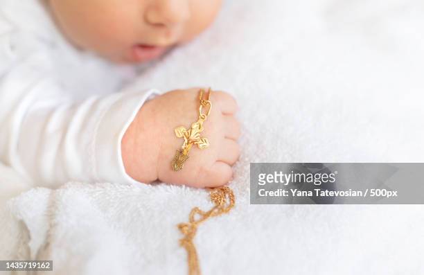 the sacrament of the baptism of a child the kid is holding a cross - catholic baptism stock-fotos und bilder