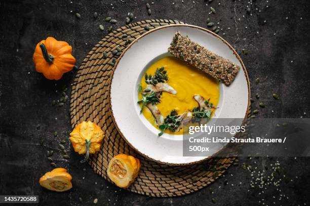 high angle view of pumpkin soup with autumn leaves on table - kürbissuppe stock-fotos und bilder