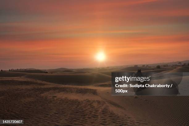 person walking on sand dune with camel in desert against sky during sunset,jaisalmer,rajasthan,india - jaisalmer stock pictures, royalty-free photos & images