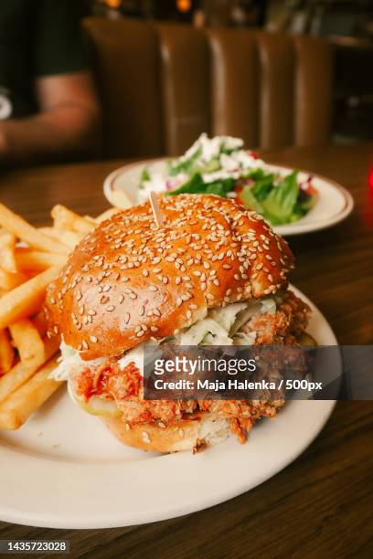 pulled chicken burger with fries on table in diner - kipburger stockfoto's en -beelden
