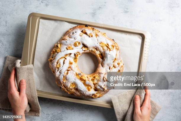 womens hands hold a baking tray with a braided yeast bun in the shape - rosca de reyes stockfoto's en -beelden