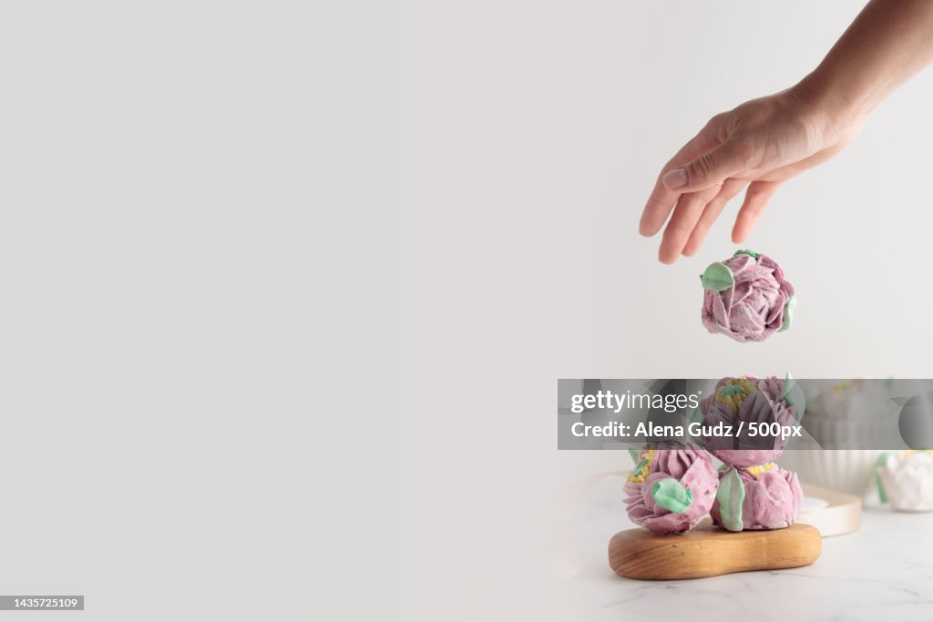 Traditional Russian homemade merengue marshmallow or zephyr flowers with a human hand,Finland