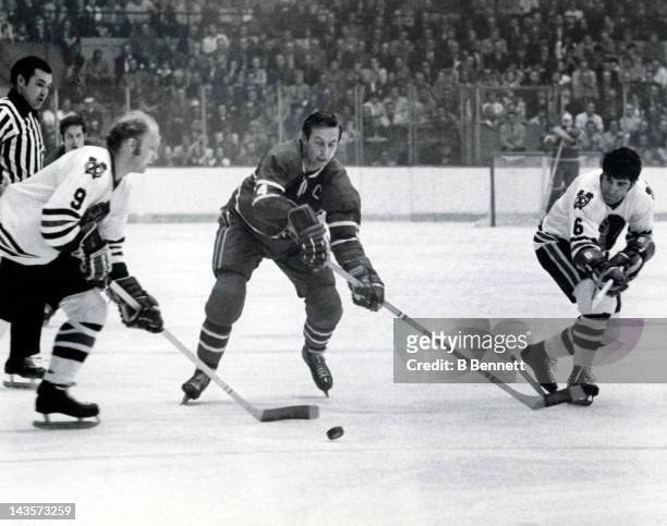 Jean Beliveau of the Montreal Canadiens tries to go for the puck as Bobby Hull and Lou Angotti of the Chicago Blackhawks take control during Game 7...
