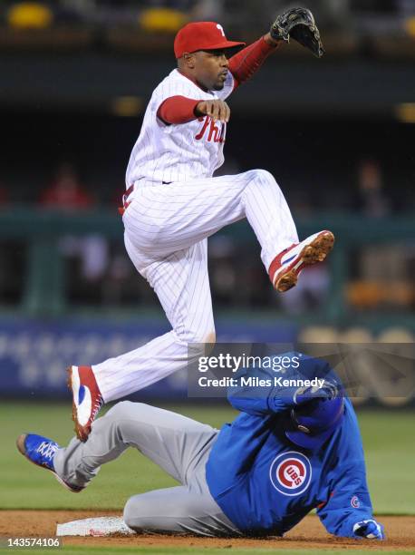 Jimmy Rollins of the Philadelphia Phillies leaps over Randy Wells of the Chicago Cubs after throwing to first base to complete a double play in the...