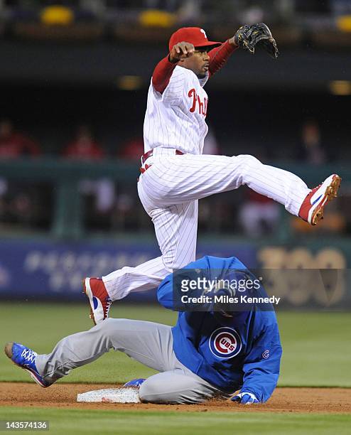 Jimmy Rollins of the Philadelphia Phillies leaps over Randy Wells of the Chicago Cubs after throwing to first base to complete a double play in the...