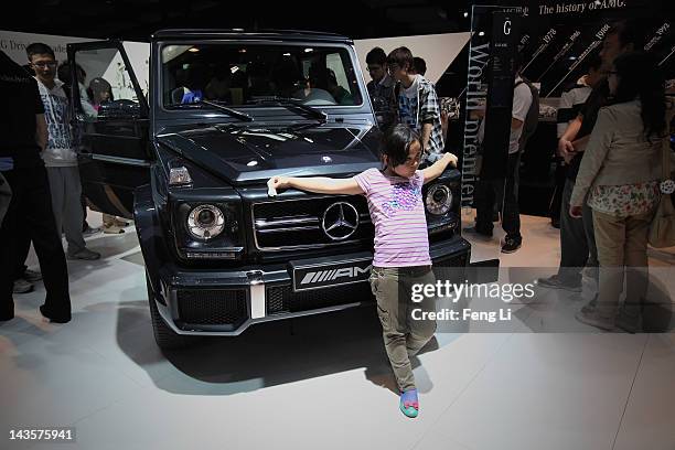 Chinese girl poses beside a Mercedes-Benz Class G 63 AMG car during the 2012 Beijing International Automotive Exhibition at China International...