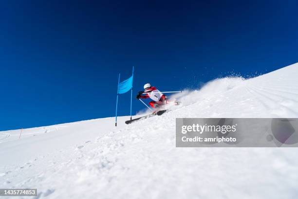 alpine ski racer skiing close to giant slalom gate - professional skier stock pictures, royalty-free photos & images