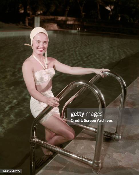 Ann Blyth wearing vintage bikini and swimming cap as she emerges from pool in a publicity pose circa 1950.