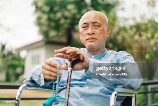 negative emotion  asian seniors sit in wheelchair and pray, missing someone and feeling lonely  at health care center - senior spirituality stock pictures, royalty-free photos & images