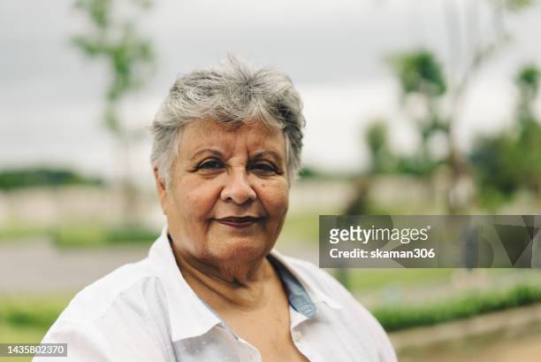 facial expression positive emotion portrait asian active senior with green background copyspace - 50 year old indian lady stock pictures, royalty-free photos & images