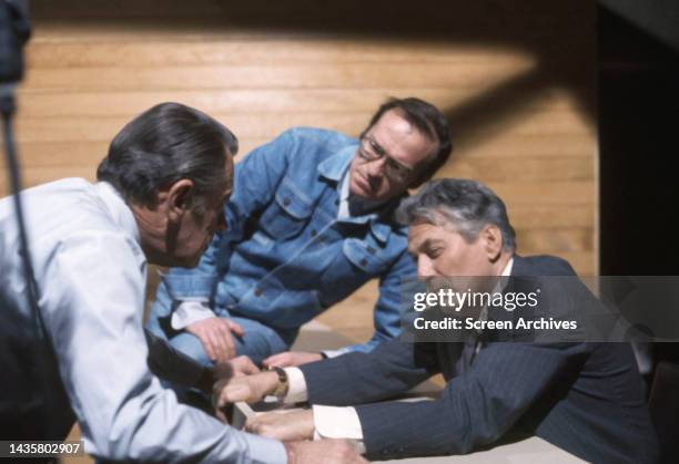 Director Sidney Lumet discusses scene with stars William Holden and Peter Finch during the filming of his 1976 drama Network.