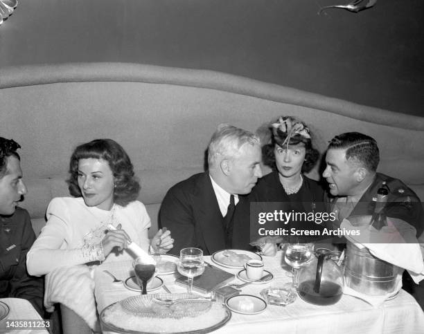 Charles Charlie Chaplin and Paulette Goddard sitting with World War 2 servicemen at restaurant circa 1944.