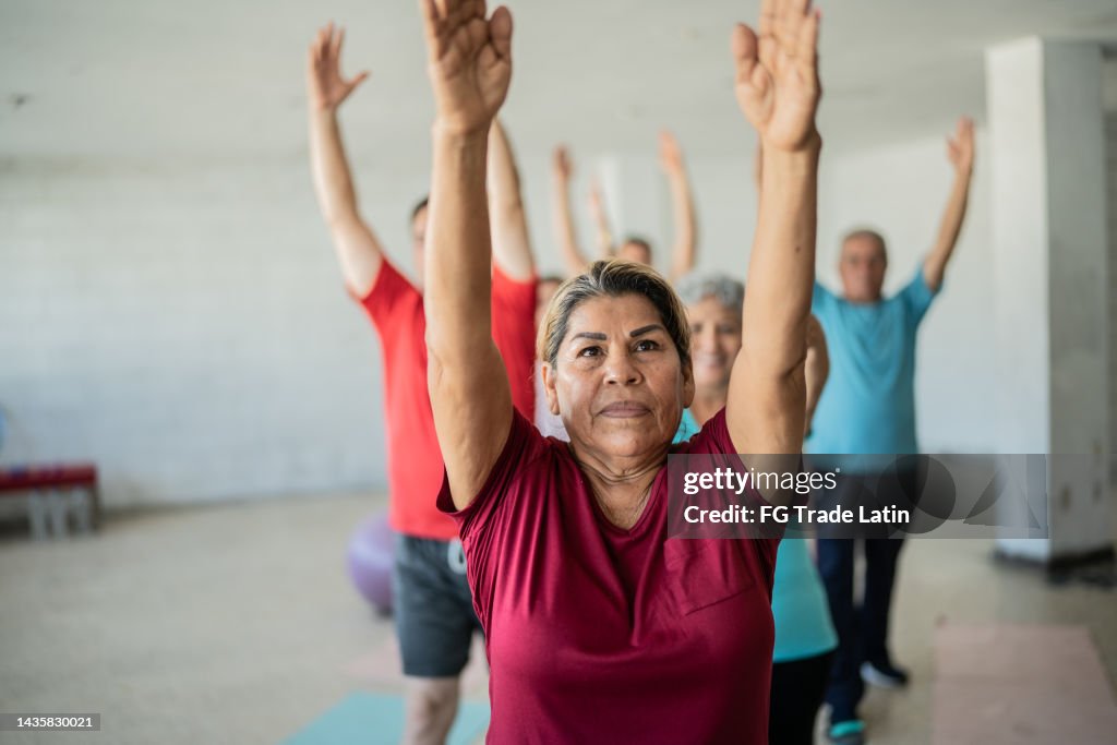 Senior woman stretching with classmates at the yoga studio