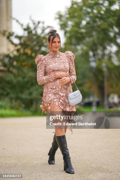 Guest wears diamonds earrings, a beige with embroidered moon and stars pattern turtleneck / puffy shoulder / long sleeves short dress, a black shiny...