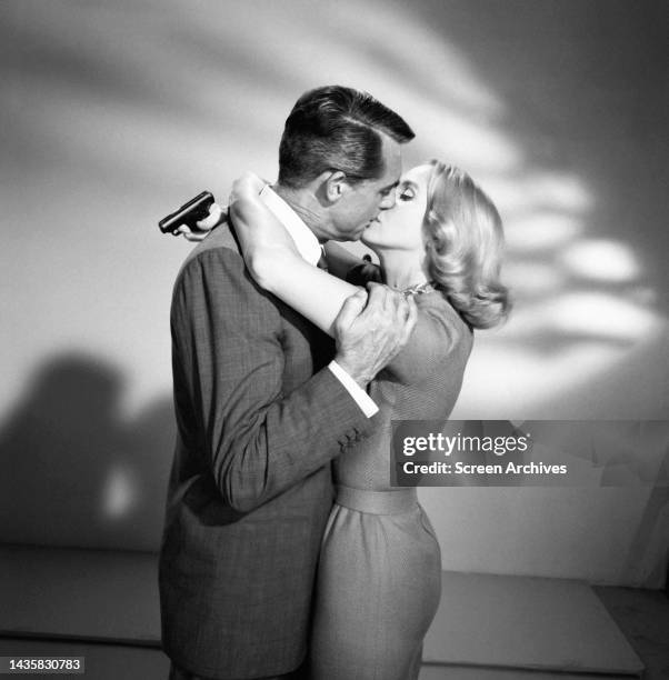 North By Northwest Cary Grant kisses Eva Marie Saint as she holds gun behind his back in a publicity portrait for the 1959 Alfred Hitchcock thriller.