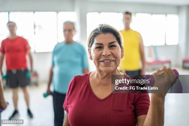 portrait of senior woman lifting weights with classmates at the gym - self discipline imagens e fotografias de stock