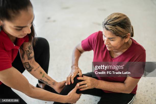 senior woman being helped by fitness instructor about pain on her knee - personal training stock pictures, royalty-free photos & images
