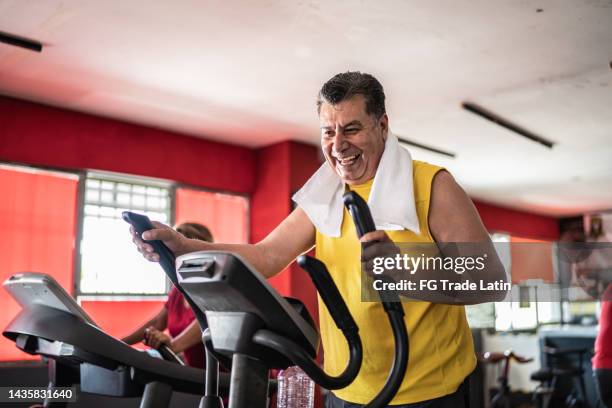 älterer mann trainiert auf einem laufband im fitnessstudio - cross trainer stock-fotos und bilder