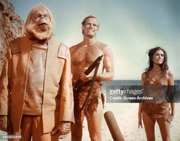 Planet of the Apes Charlton Heston holding rifle with Linda Harrison and Maurice Evans as Dr Zaius on beach from the 1968 film.