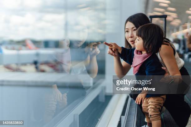 headshot of mother and toddler looking at view at the airport - family at airport fotografías e imágenes de stock