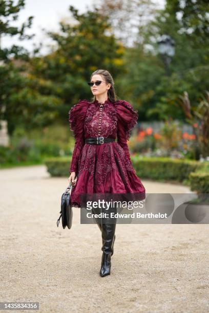 Guest wears black cat eyes sunglasses, silver earrings, a burgundy lace print pattern / cut-out and embroidered rhinestones flower puffy shoulder /...