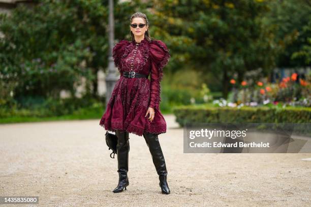 Guest wears black cat eyes sunglasses, silver earrings, a burgundy lace print pattern / cut-out and embroidered rhinestones flower puffy shoulder /...