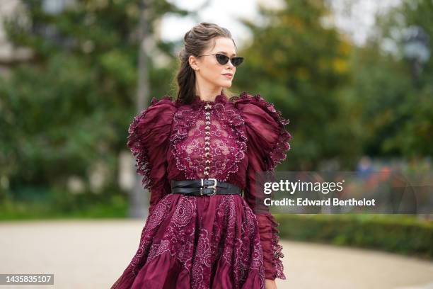 Guest wears black cat eyes sunglasses, silver earrings, a burgundy lace print pattern / cut-out and embroidered rhinestones flower puffy shoulder /...