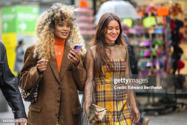 Guest wears a silver chain pendants necklace, a neon orange wool turtleneck pullover, a khaki and orange houndstooth print pattern wool oversized...