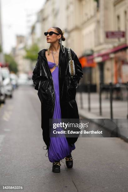 Guest wears black sunglasses from Stella McCartney with silver and gold large chain details, silver earrings, a silver chain handcuffs pendant...