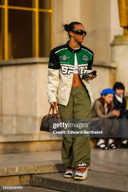 Guest wears black sunglasses from Prada, silver and diamonds earrings, a white t-shirt, a silver and diamonds necklace, a white cropped t-shirt, a...