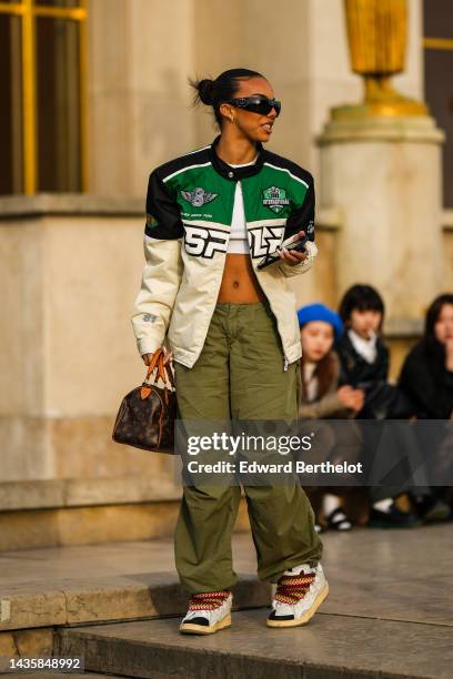 Guest wears black sunglasses from Prada, silver and diamonds earrings, a white t-shirt, a silver and diamonds necklace, a white cropped t-shirt, a...