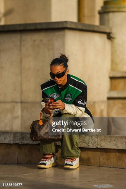 Guest wears black sunglasses from Prada, silver and diamonds earrings, a white t-shirt, a silver and diamonds necklace, a white cropped t-shirt, a...