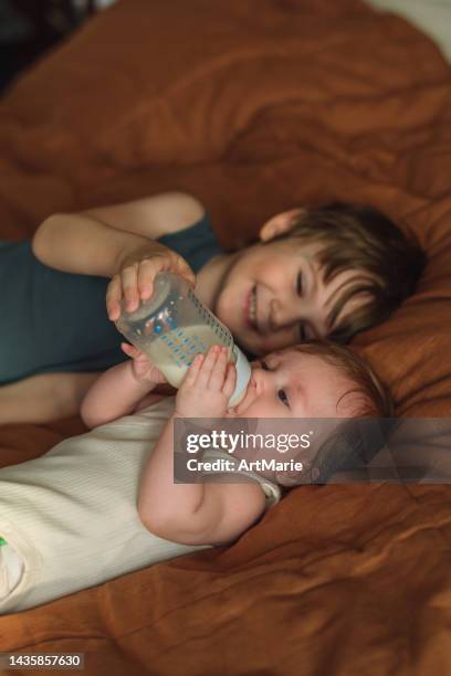 little boy feeding his cute baby sister - sisters feeding stockfoto's en -beelden