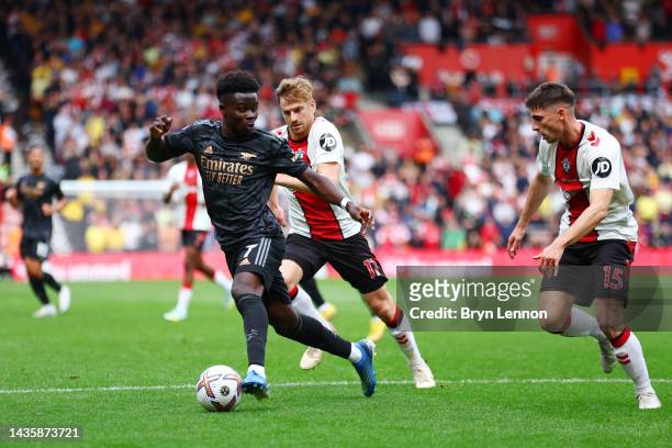 Bukayo Saka of Arsenal is challenged by Stuart Armstrong and Romain Perraud of Southampton during the Premier League match between Southampton FC and...