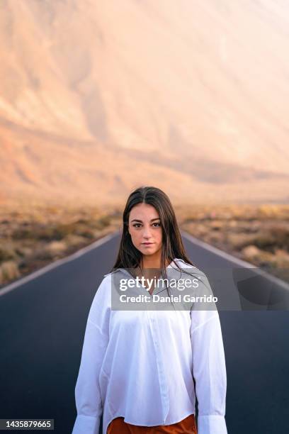 girl with long black hair in a white shirt in the middle of the teide road in tenerife, portrait photography, tenerife - crossing the road stock pictures, royalty-free photos & images