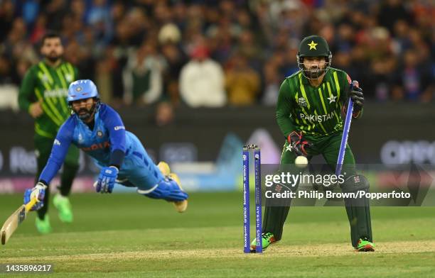 Mohammad Rizwan of Pakistan holds a stump as Dinesh Karthik of India dives to make his ground during the ICC Men's T20 World Cup match between India...