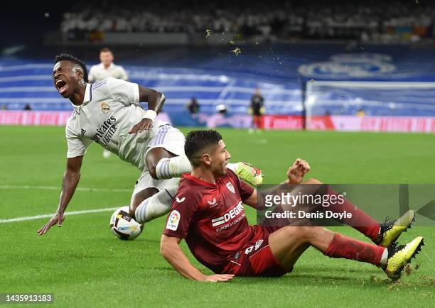 Vinicius Junior of Real Madrid is tackled by Gonzalo Montiel of Sevilla FC during the LaLiga Santander match between Real Madrid CF and Sevilla FC at...