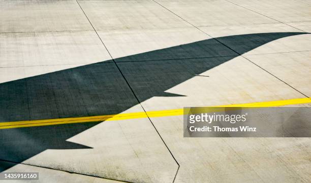 shadow of an airplane wing on the runway - runway stock-fotos und bilder