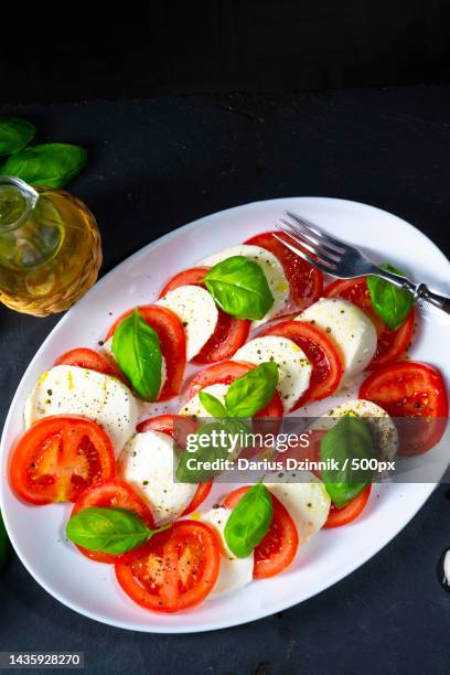 high angle view of salad in plate on black background - caprese salad stock pictures, royalty-free photos & images