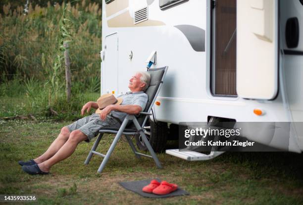 senior man relaxing on deck chair outside camper van - sedia a sdraio foto e immagini stock