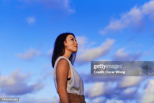 confident young asian woman looking up the sky - japanese woman looking up stock-fotos und bilder