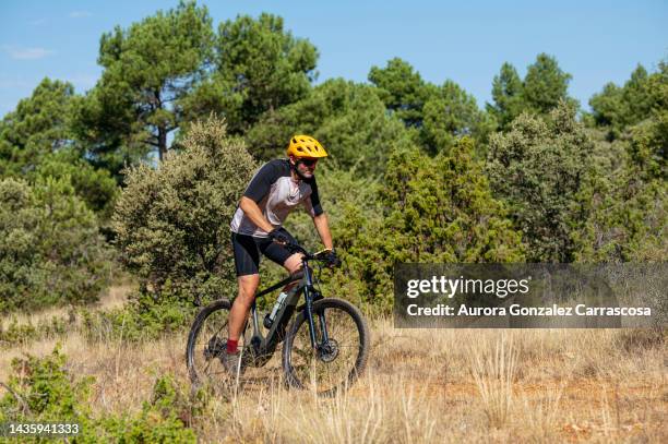 man spending a day of leisure and sport with an electric mountain bike in the countryside. - provincie guadalajara stockfoto's en -beelden