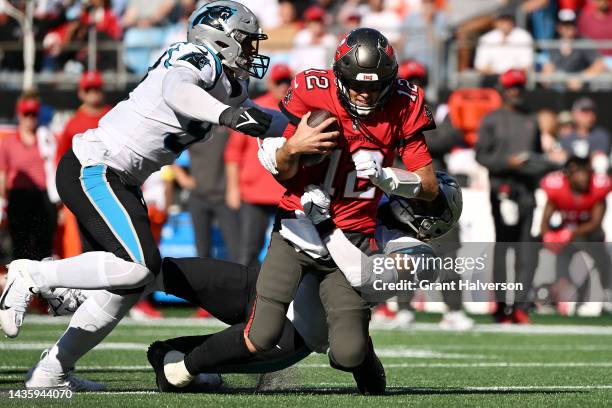 Frankie Luvu of the Carolina Panthers tackles Tom Brady of the Tampa Bay Buccaneers in the third quarter at Bank of America Stadium on October 23,...