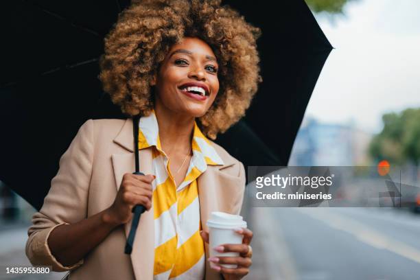 portrait of an elegant african american woman with paper cup standing on the street - drink umbrella stock pictures, royalty-free photos & images
