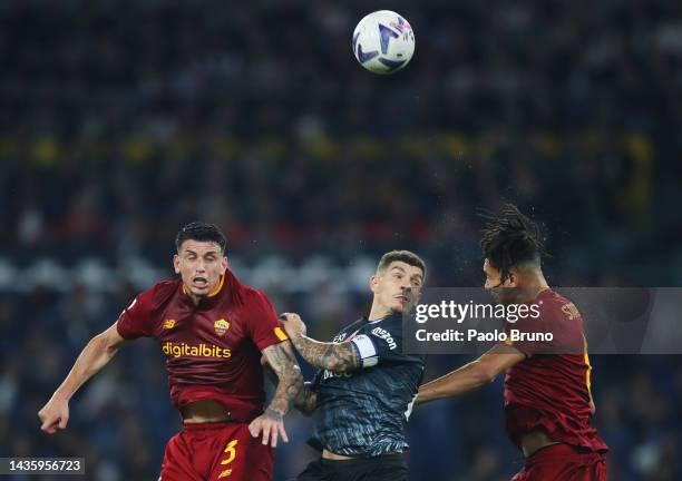Giovanni Di Lorenzo of SSC Napoli jumps for the ball with Roger Ibanez and Chris Smalling of AS Roma during the Serie A match between AS Roma and SSC...