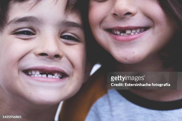 portrait of a boy and a girl smiling, who have lost two teeth - tooth fairy stock pictures, royalty-free photos & images