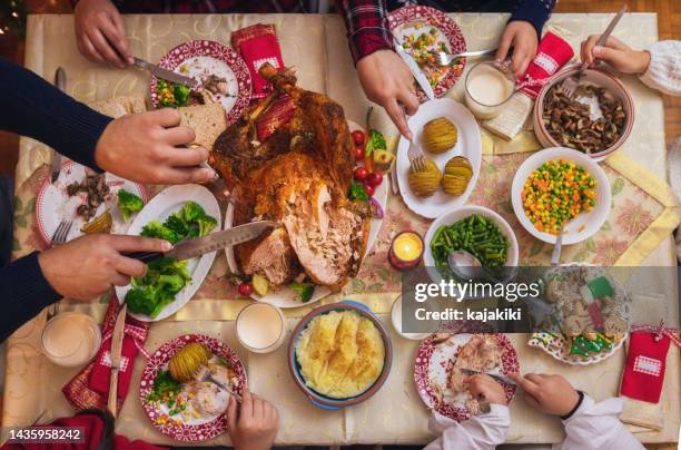 young father carving stuffed roasted turkey for christmas dinner - new years eve dinner stock pictures, royalty-free photos & images