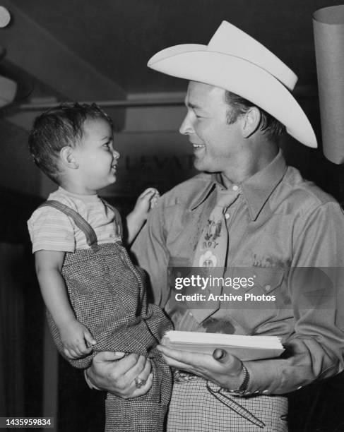 Roy Rogers smiles as he holds his baby boy Roy Jr., United States, circa 1942.